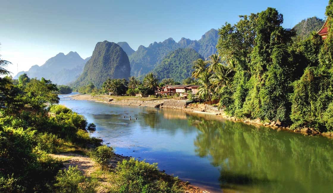 Sunset over the Mekong River with traditional stilt houses along the banks. 