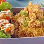 Sepiring bihun goreng ayam dengan potongan ayam dan sayuran segar, disajikan hangat dengan taburan bawang goreng