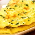 Sepiring sawi omelet hangat dengan warna keemasan, disajikan dengan irisan tomat cherry