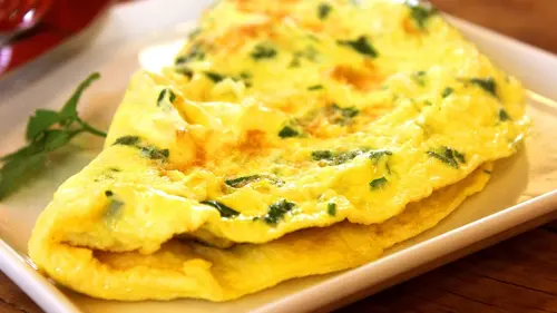 Sepiring sawi omelet hangat dengan warna keemasan, disajikan dengan irisan tomat cherry