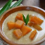 Bubur Labu Kuning Tradisional: Seporsi Bubur Labu Kuning dengan warna cerah, disajikan dengan kuah santan kental dan gula merah yang manis